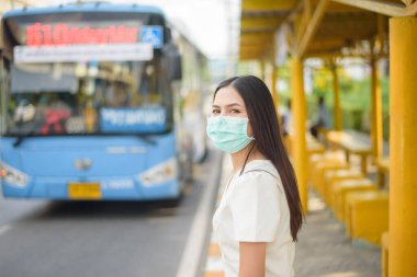 Otobüs durağında güzel bir kadın maske takıyor. 