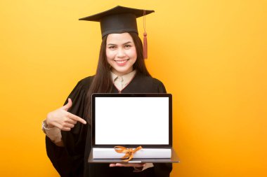 Mezuniyet elbisesi giymiş güzel bir kadın dizüstü bilgisayar modeli tutuyor. 