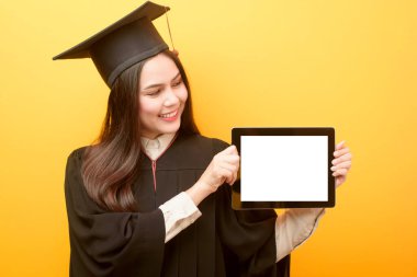 Mezuniyet elbisesi içindeki güzel kadın elinde tablet maketi tutuyor.