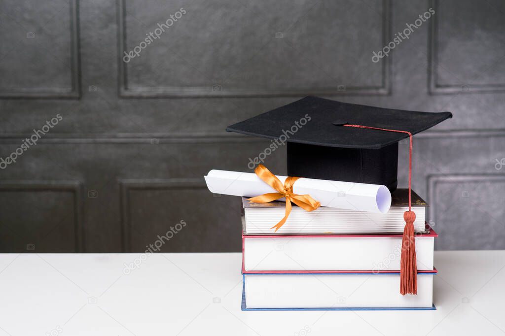 Graduation cap with books on white desk , Education background 