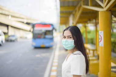 Otobüs durağında güzel bir kadın maske takıyor. 