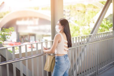 Yüzü maskeli genç kadın şehir dışında duruyor. 