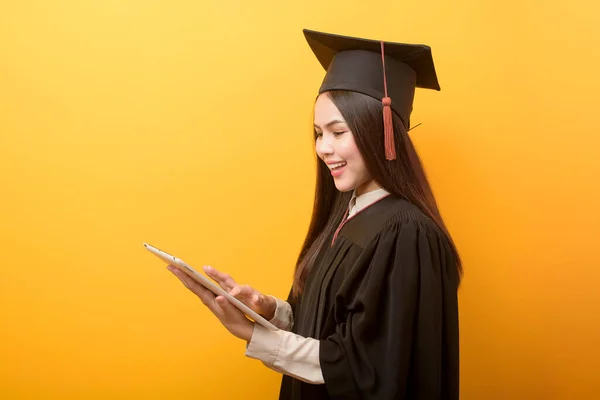 Portrait Beautiful Woman Graduation Gown Holding Tablet Yellow Background — Stock Photo, Image