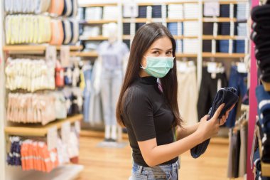 Yüzü maskeli kadın alışveriş merkezinde alışveriş yapıyor. 