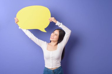 Genç bir kadın mor arka planda sarı boş bir konuşma yapıyor. 