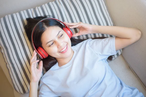 一位年轻妇女正在客厅里用耳机欣赏音乐 这是家庭安全的概念 — 图库照片