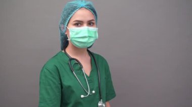 Üniformalı genç kadın doktor portresi gri arka planda kendine güveniyor. 