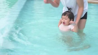 Mutlu bir Asyalı anne ve kız havuz, yaşam tarzı, ebeveynlik ve aile kavramı içinde yüzmekten zevk alır.