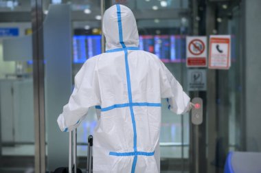 Asyalı bir adam havaalanı asansöründe kostüm giyiyor, güvenlik seyahati, covid-19 koruma, sosyal mesafe konsepti. .