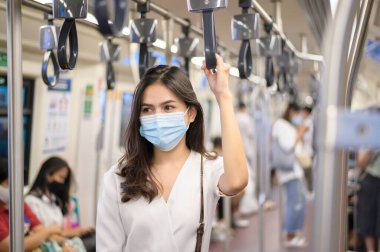 Genç bir kadın metro, covid-19 koruma, güvenlik seyahati, yeni normal, sosyal uzaklık, güvenlik ulaşımı, salgın konseptiyle seyahat ederken koruyucu maske takıyor. .