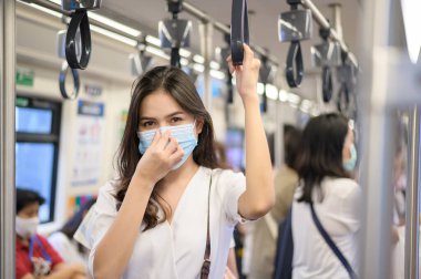 Genç bir kadın metro, covid-19 koruma, güvenlik seyahati, yeni normal, sosyal uzaklık, güvenlik ulaşımı, salgın konseptiyle seyahat ederken koruyucu maske takıyor. .
