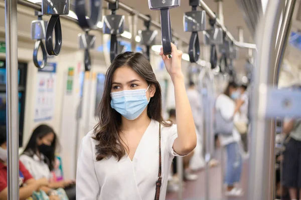 Genç bir kadın metro, covid-19 koruma, güvenlik seyahati, yeni normal, sosyal uzaklık, güvenlik ulaşımı, salgın konseptiyle seyahat ederken koruyucu maske takıyor. .