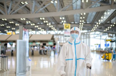 Asyalı bir adam uluslararası havaalanında kostüm giyiyor, güvenlik seyahati, covid-19 koruma, sosyal uzaklık konsepti .