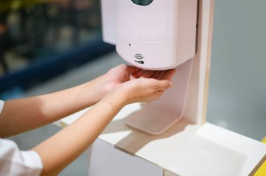 Yakın çekim kadın eli, alışveriş merkezinde alkol jeli kullanıyor, covid-19 koruma kavramı. . 