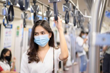 Genç bir kadın metro, covid-19 koruma, güvenlik seyahati, yeni normal, sosyal uzaklık, güvenlik ulaşımı, salgın konseptiyle seyahat ederken koruyucu maske takıyor. .