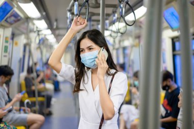 Genç bir kadın metro, covid-19 koruma, güvenlik seyahati, yeni normal, sosyal uzaklık, güvenlik ulaşımı, salgın konseptiyle seyahat ederken koruyucu maske takıyor. .