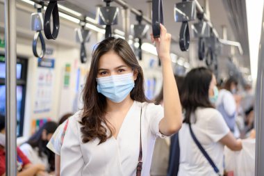 Genç bir kadın metro, covid-19 koruma, güvenlik seyahati, yeni normal, sosyal uzaklık, güvenlik ulaşımı, salgın konseptiyle seyahat ederken koruyucu maske takıyor. .