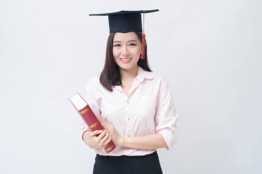 Beyaz arka plan stüdyosu ve eğitim konsepti üzerinde eğitim şapkası olan güzel Asyalı genç bir kadının portresi. . 