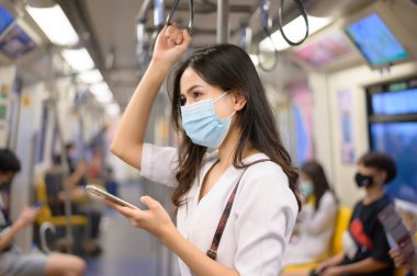 Genç bir kadın metro, covid-19 koruma, güvenlik seyahati, yeni normal, sosyal uzaklık, güvenlik ulaşımı, salgın konseptiyle seyahat ederken koruyucu maske takıyor. .