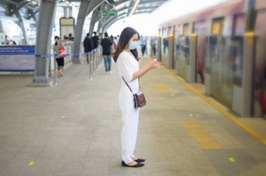 Genç bir kadın metro istasyonunda duruyor, maske takıyor, Covid-19 koruma, yeni normal seyahat konsepti.