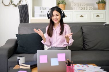 Kulaklık takan genç ve güzel bir kadın görüntülü konferans yapıyor.