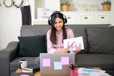 Kulaklık takan genç ve güzel bir kadın görüntülü konferans yapıyor.