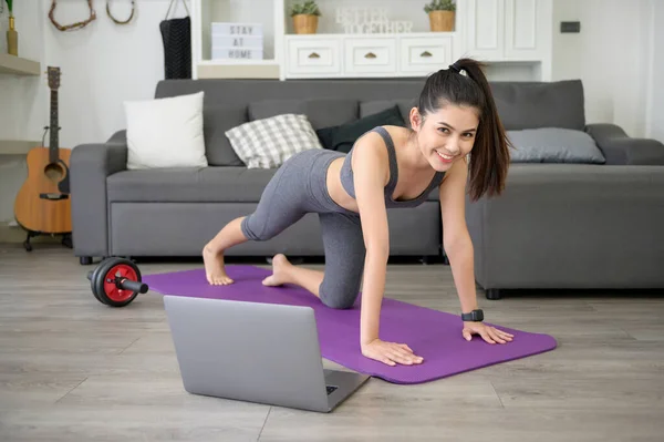 A Young beautiful woman is doing the mountain climber exercise at home