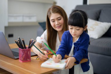 Asyalı Mutlu anne ve kızı evde internet üzerinden çalışmak için dizüstü bilgisayar kullanıyorlar. Karantina zamanında e-öğrenim kavramı