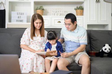 Mutlu Asyalı ebeveyn küçük tatlı kızına ev ödevi yapmayı öğretiyor ve evde resim çiziyor.. 