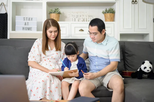 Mutlu Asyalı ebeveyn küçük tatlı kızına ev ödevi yapmayı öğretiyor ve evde resim çiziyor.. 