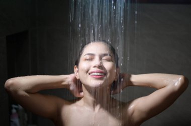 Genç ve güzel bir kadın evdeki banyoda duş alıyor.