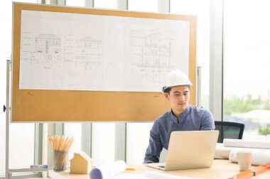 Dizüstü bilgisayar kullanan bir erkek mühendis, müşteri ya da iş ortağıyla görüntülü görüşme yapıyor,  