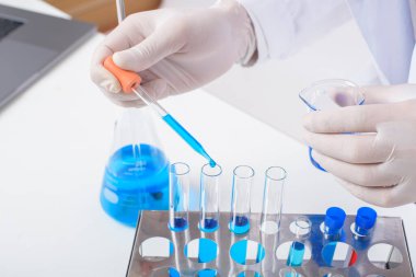 Bilimadamları laboratuvarda izole edilmiş beyaz arka planda bazı mavi sıvı kimyasalları test edip araştırıyorlar..