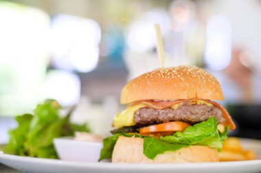 Bir tabak dolusu lezzetli hamburger, biftek, domates, peynir ve marul.
