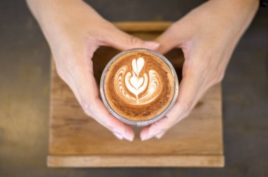 Ahşap masa arkasında sıcak latte sanatının en üst görüntüsü.