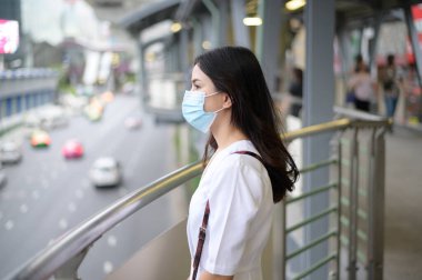 Sokak şehrinde yüz maskesi takan genç bir kadın, Coronavirus koruması, salgın altında yaşam tarzı, sağlık konsepti.