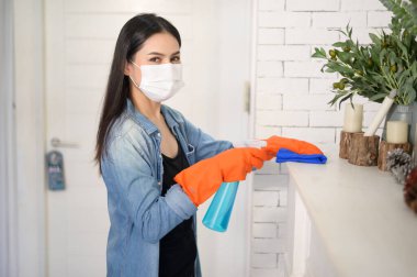 Temizlik eldivenli bir kadın evi temizlemek için alkol spreyi kullanıyor. Sağlıklı ve tıbbi. Ev konseptinde Cvid-19 koruması. .