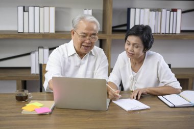 Mutlu bir Asyalı çift internette sörf yaparak ve ailesiyle web kamerasında konuşarak vakit geçiriyor, emeklilik kavramı..