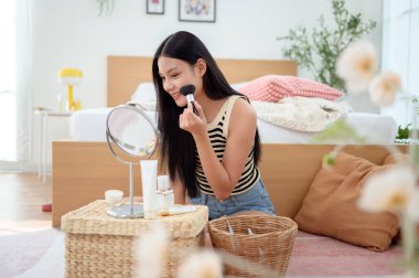 Genç Asyalı kadın evde makyaj yapıyor.