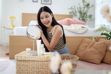 Genç Asyalı kadın evde makyaj yapıyor.