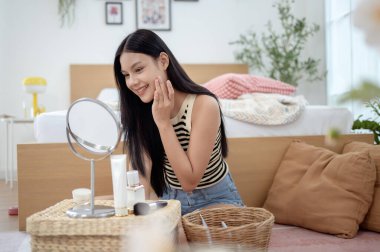 Genç Asyalı kadın evde makyaj yapıyor.