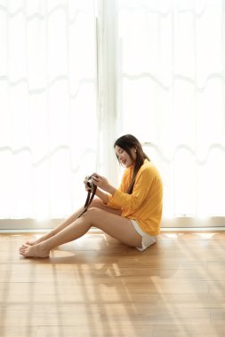 Genç Asyalı kadın evdeki oturma odasında kamera kullanıyor. 