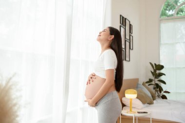 Mutlu gülümseyen hamile kadın yatak odasında.