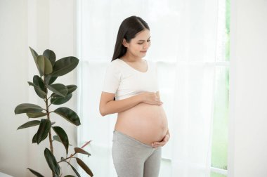 Mutlu gülümseyen hamile kadın yatak odasında.