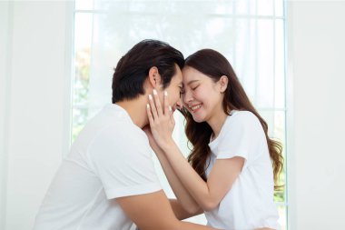 Işıl ışıl bir yatak odasında bir yatakta otururken iki insan sıcak bir kucaklaşmayı paylaşıyor..