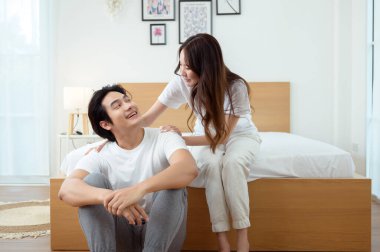 Işıl ışıl bir yatak odasında bir yatakta otururken iki insan sıcak bir kucaklaşmayı paylaşıyor..