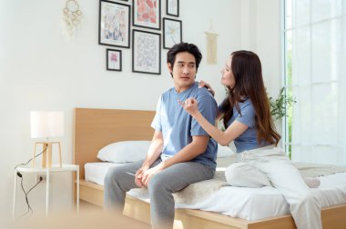 Işıl ışıl bir yatak odasında bir yatakta otururken iki insan sıcak bir kucaklaşmayı paylaşıyor..