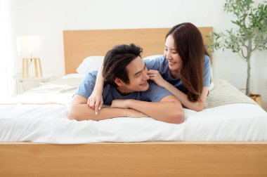 Işıl ışıl bir yatak odasında bir yatakta otururken iki insan sıcak bir kucaklaşmayı paylaşıyor..