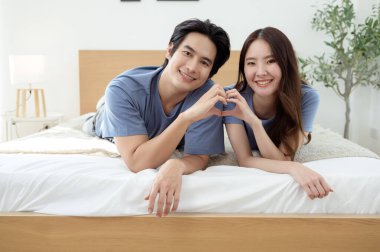 Işıl ışıl bir yatak odasında bir yatakta otururken iki insan sıcak bir kucaklaşmayı paylaşıyor..