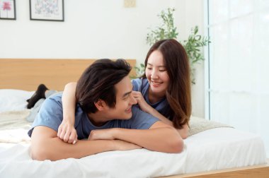 Işıl ışıl bir yatak odasında bir yatakta otururken iki insan sıcak bir kucaklaşmayı paylaşıyor..